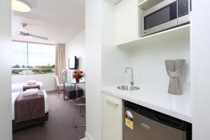 uma cozinha com um lavatório e um quarto com uma cama em PA Apartments em Brisbane