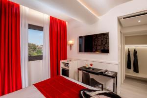 1 dormitorio con cortinas rojas, escritorio y cama en Hotel American Palace Eur, en Roma