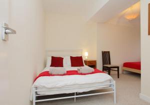 a bedroom with a white bed with red pillows at Large Cosy House Ideal for Corporate Lets in Andover