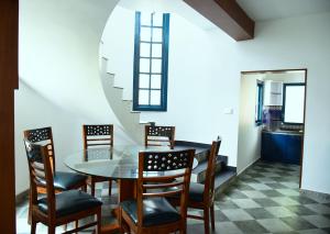 a dining room with a glass table and chairs at Hydrangea Villa in Kodaikānāl
