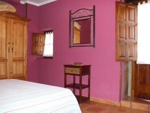 een slaapkamer met paarse muren en een bed en een spiegel bij Apartamentos La Corraliza in Totero