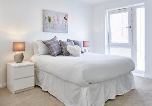 a white bedroom with a large white bed with pillows at ShortstayMK Campbell Park serviced houses, with free superfast wi-fi, parking, Sky sports and movies in Milton Keynes
