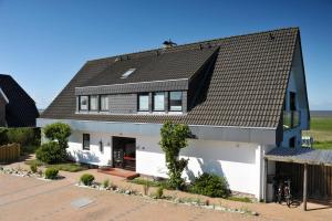 una casa con techo negro y garaje blanco en Ferienwohnung Feskerdam, en Morsum