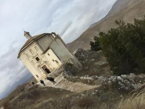an old building on the side of a mountain at Itaka in LʼAquila