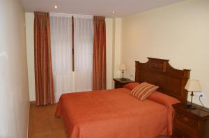 1 dormitorio con 1 cama con manta naranja en Apartamentos Don Clemente, en Las Rozas