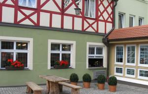 - un bâtiment avec une table de pique-nique devant dans l'établissement Traditionsgasthof Grüner Baum, à Bad Staffelstein