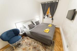 ein Schlafzimmer mit einem Bett und einem blauen Stuhl in der Unterkunft Babylon Apartmány in Český Krumlov