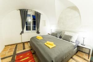 Un dormitorio con una cama con toallas amarillas. en Babylon Apartmány en Český Krumlov