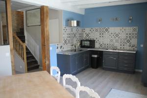 eine Küche mit blauen Wänden sowie einem Tisch und Stühlen in der Unterkunft le kerente in Vibrac