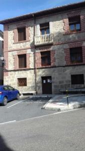 ein blaues Auto, das vor einem Backsteingebäude parkt in der Unterkunft Casa Rural Rio Canto in El Hornillo
