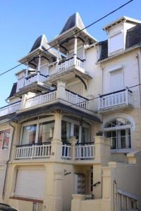 Una gran casa blanca con balcones en un lateral. en Appartement Les Confidences, en Le Touquet-Paris-Plage