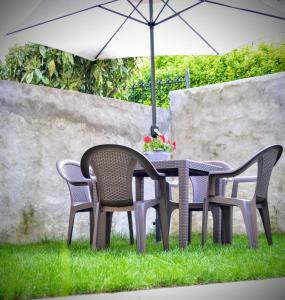 a table and chairs with an umbrella on the grass at Casina dello Zio in Verbania