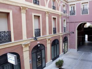różowy budynek z czarnymi drzwiami i oknami w obiekcie Apartamento nuevo y de lujo en puerta del sol w Madrycie