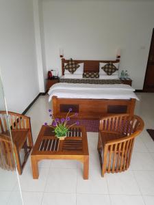 a bedroom with a bed and two chairs and a table at The Grand Bandarawela in Bandarawela
