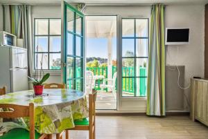 ein Esszimmer mit einem Tisch und einem Balkon in der Unterkunft Residence Port Bourgenay - maeva Home in Talmont