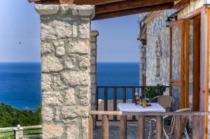 a table on a balcony with a view of the ocean at Nireas : Stone Villa in Zakynthos