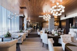 a restaurant with white chairs and tables and chandeliers at Grand Hotel Oka Premium in Nizhny Novgorod