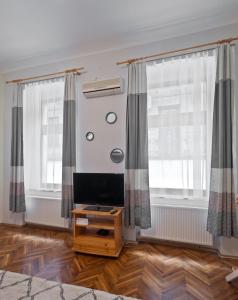 - un salon avec une télévision et 2 fenêtres dans l'établissement Capital Center Apartments Üllői, à Budapest