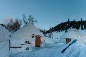 um grupo de casas de iglu na neve em Jyrgalan Yurt Lodge em Dzhergalan