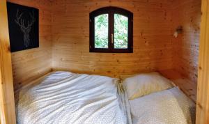 een kleine kamer met een bed in een hut met een raam bij Roulotte Comtoise à Strasbourg in Straatsburg