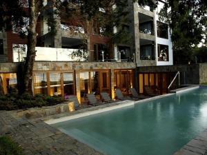 a swimming pool in front of a building at Hotel Playa Grande Suites in Pucón
