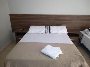 a bed with white sheets and pillows on it at Flex Hotel in Três Lagoas