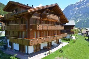 ein großes Gebäude mit Holzbalkonen und einem Berg in der Unterkunft Apartment Bränderli - GRIWA RENT AG in Grindelwald