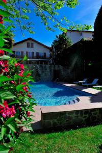 a swimming pool in a yard with a house in the background at Hôtel des Pyrénées in Saint-Jean-Pied-de-Port