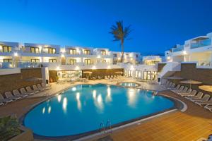 a swimming pool in front of a hotel at night at Aqua Suites in Puerto del Carmen