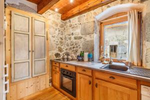 a kitchen with wooden cabinets and a sink and a window at Maison de caractère dans la chartreuse in Saint-Pierre-de-Chartreuse