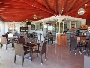 a restaurant with wooden ceilings and tables and chairs at Loutsiana Deluxe Apts in Ayia Napa