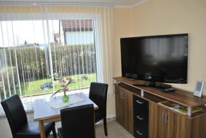 ein Wohnzimmer mit einem TV und einem Tisch mit Stühlen in der Unterkunft Guest house Mückenheim in Benneckenstein