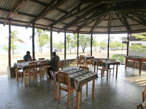 two people sitting at a restaurant with tables and chairs at Matema Lake Shore Resort in Matema Beach