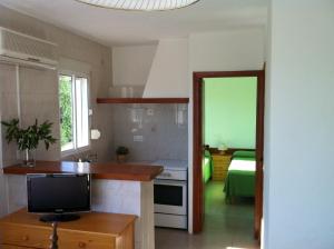 una cucina con televisore e una camera con un letto di Apartamentos Eugenio la Sabina a La Savina