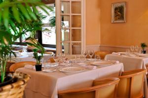 a restaurant with white tables and chairs with wine glasses at Hôtel des Pyrénées in Saint-Jean-Pied-de-Port