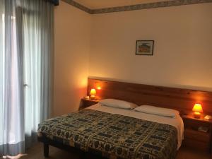 1 dormitorio con 1 cama, 2 lámparas y ventana en Hotel International, en Tarvisio