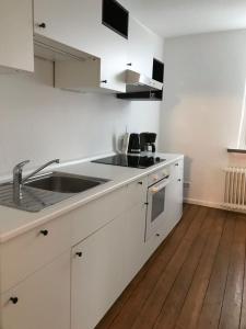 リューネブルクにあるFachwerkhaus in der Altstadtのウッドフロアのキッチン(白いキャビネット、シンク付)