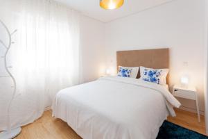 een witte slaapkamer met een groot wit bed met blauwe kussens bij Urban Views Townhouse Arrábida in Porto