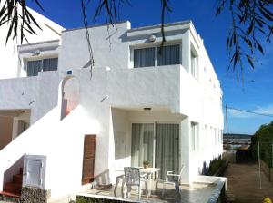 a white house with a table and chairs at Apartamentos Eugenio la Sabina in La Savina