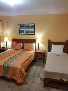 um quarto com 2 camas e 2 candeeiros nas mesas em Piarco Village Suites em Piarco