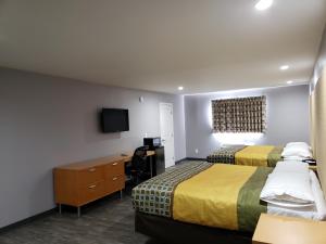 a hotel room with two beds and a desk and a tv at Regal Inn in Los Angeles