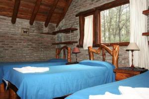 a bedroom with two blue beds and a brick wall at Cabaña La Maga in Mar Azul