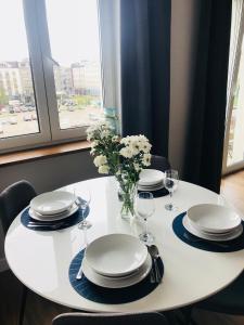une table blanche avec des assiettes, des verres et un vase de fleurs dans l'établissement Apartament 27, à Gdynia