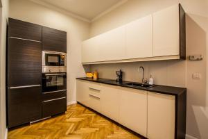 a kitchen with white cabinets and a black refrigerator at Vojtesska Apartment By Ruterra in Prague