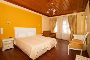 a yellow bedroom with a bed and a chair at Hotel Monodendri in Monodendri