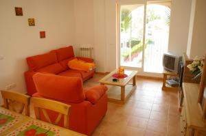 a living room with an orange couch and a table at Apartamentos Concha del Mar in Sagunto