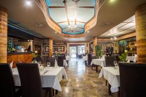 restauracja z białymi stołami i krzesłami oraz żyrandolem w obiekcie Hotel Karino Spa w Polańczyku