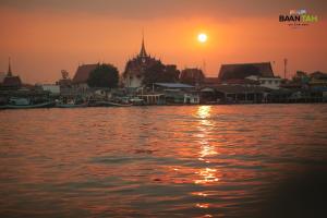 a sunset over a body of water with houses and boats at Baan Tah On The Sea in Bang Sare