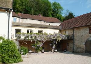 un edificio con un albero con fiori viola di Domaine de la Corgette a Saint-Romain