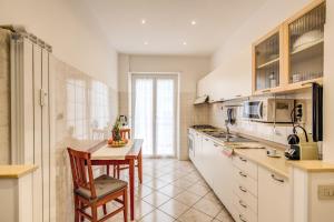 a kitchen with white cabinets and a table with a chair at Rome4Guest Ostia in Lido di Ostia